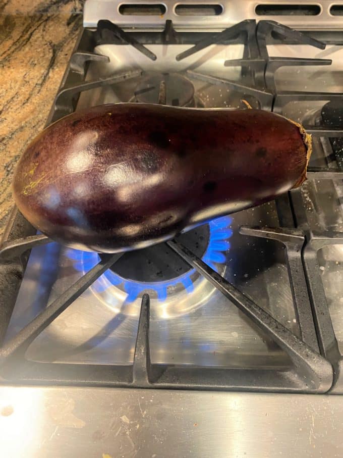 An eggplant on an open flame on a gas stove
