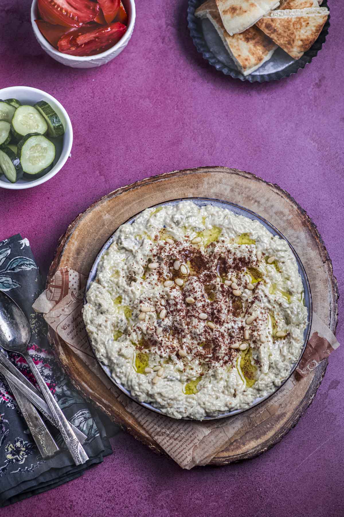 A plate of baba Ganoush on top of a round wood board
