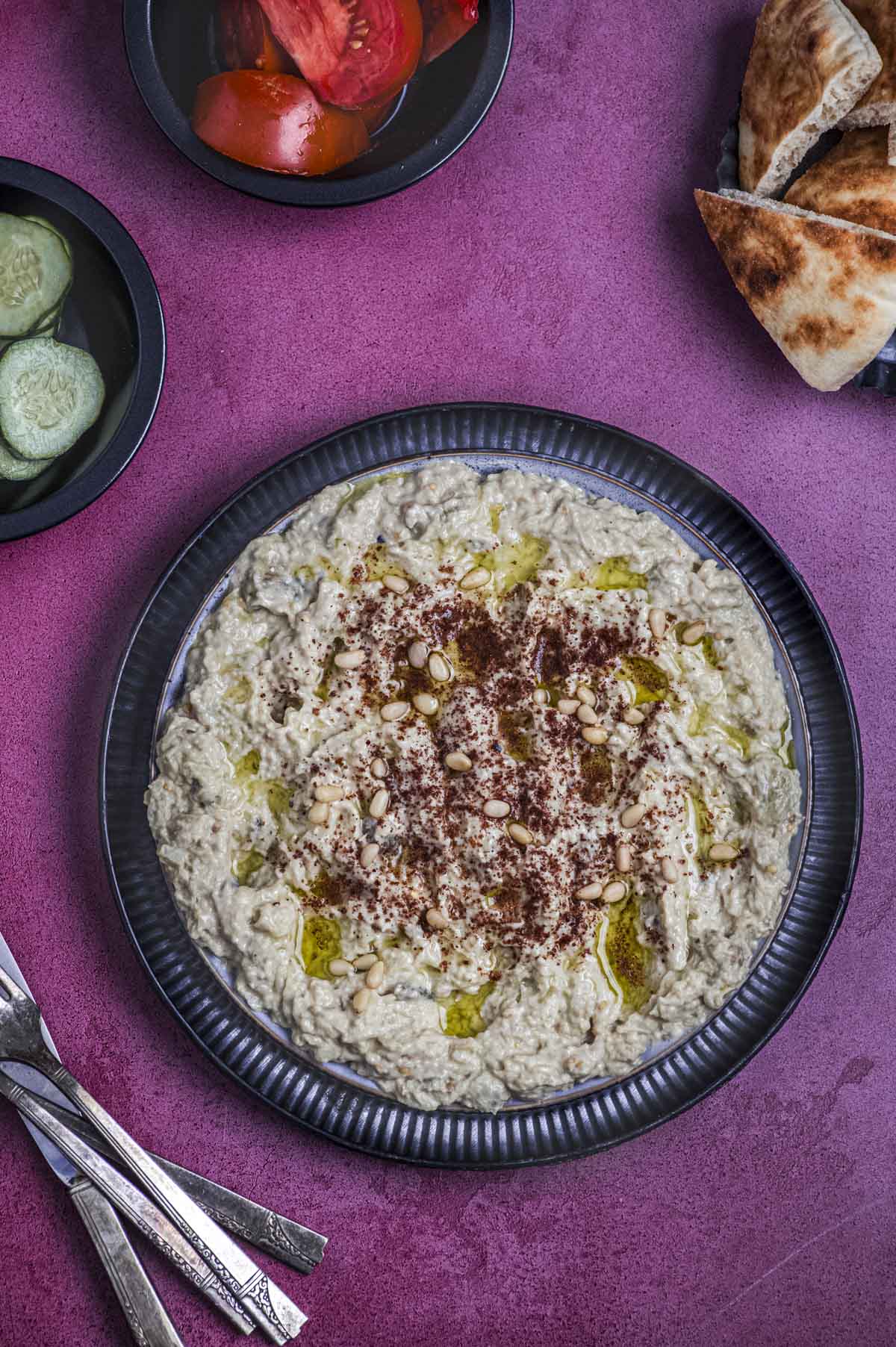 A plate of baba ganoush on a magenta surface
