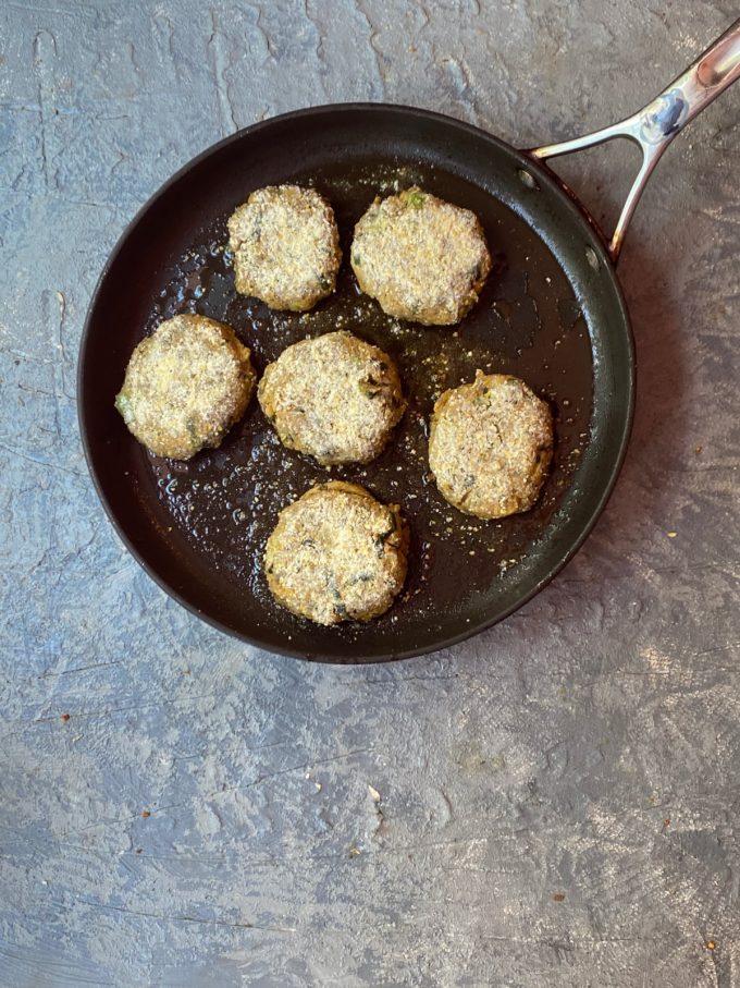 6 chickpea fritters frying in oil in a skillet
