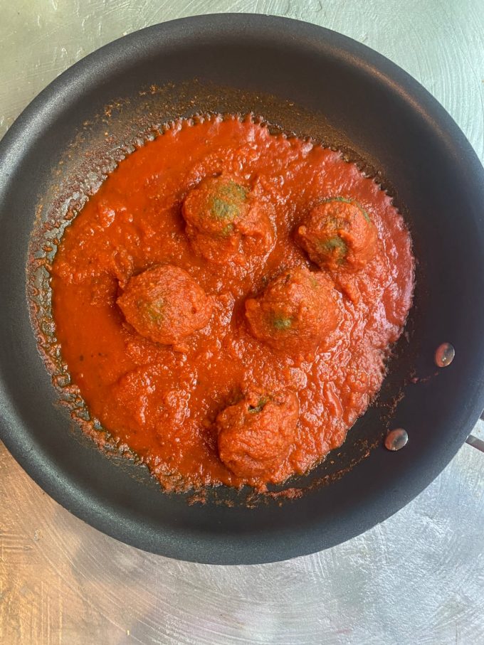 overhead shot of vegan meatballs mixed with red sauce in a skillet