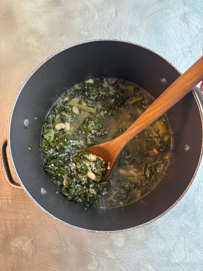 overhead shot of kale soup with veggie sausage in a pot with a serving spoon