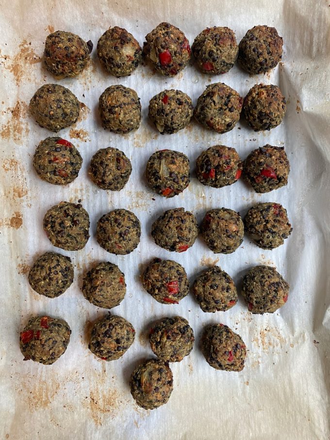 overhead image of lentil meatballs on a parchment paper lined baking sheet after being baked