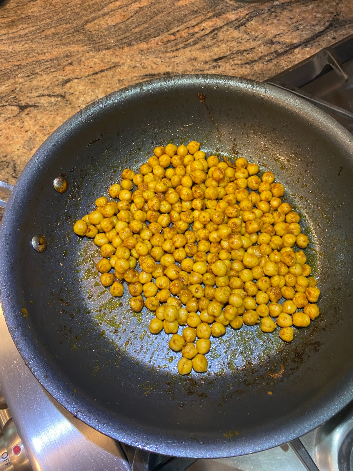 overhead view of a nonstick skillet cooking chickpeas tossed with oil and spices