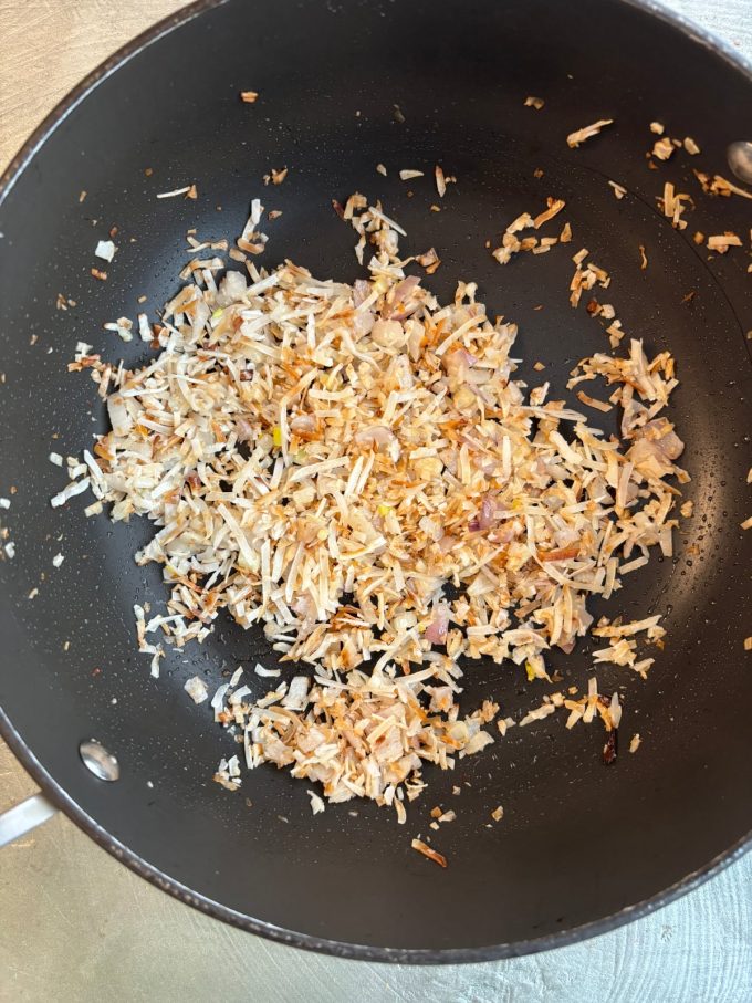 overhead image of a skillet cooking rice, coconut, and shallots.