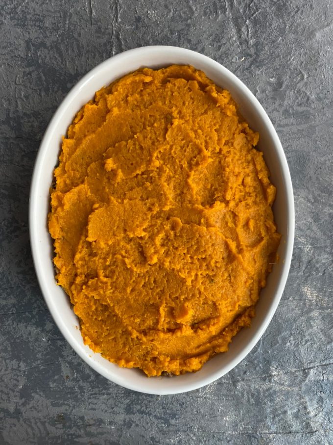 overhead image of a white oval baking dish filled with mashed sweet potatoes