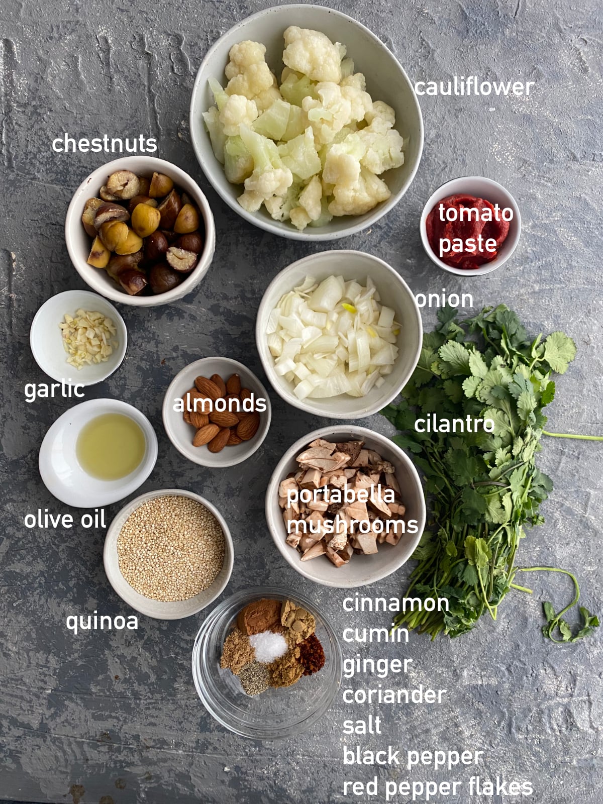 overhead image of the ingredients needed to make sweet potato shepherd's pie. Each ingredient is in a small white bowl and labeled with white text