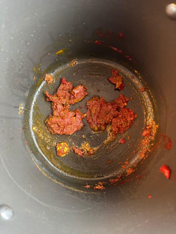 overhead image of a pot cooking tomato paste and spices