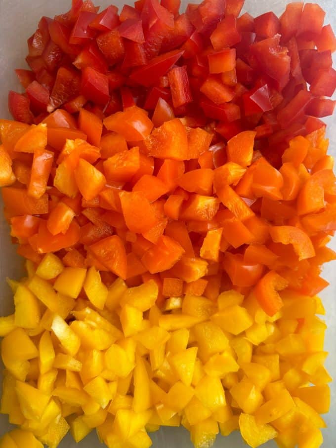 overhead image of red, orange, and yellow diced bell peppers.