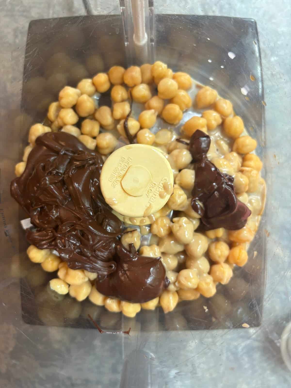 overhead image of a food processor filled with the ingredients needed to make chocolate hummus