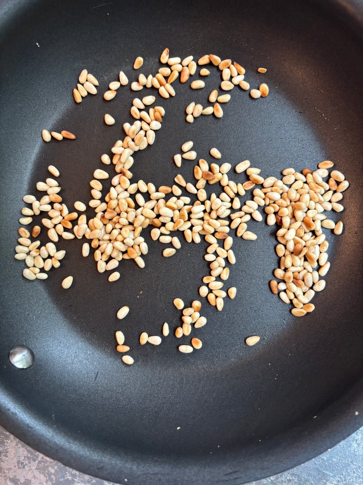 overhead image of a nonstick skillet toasting pine nuts