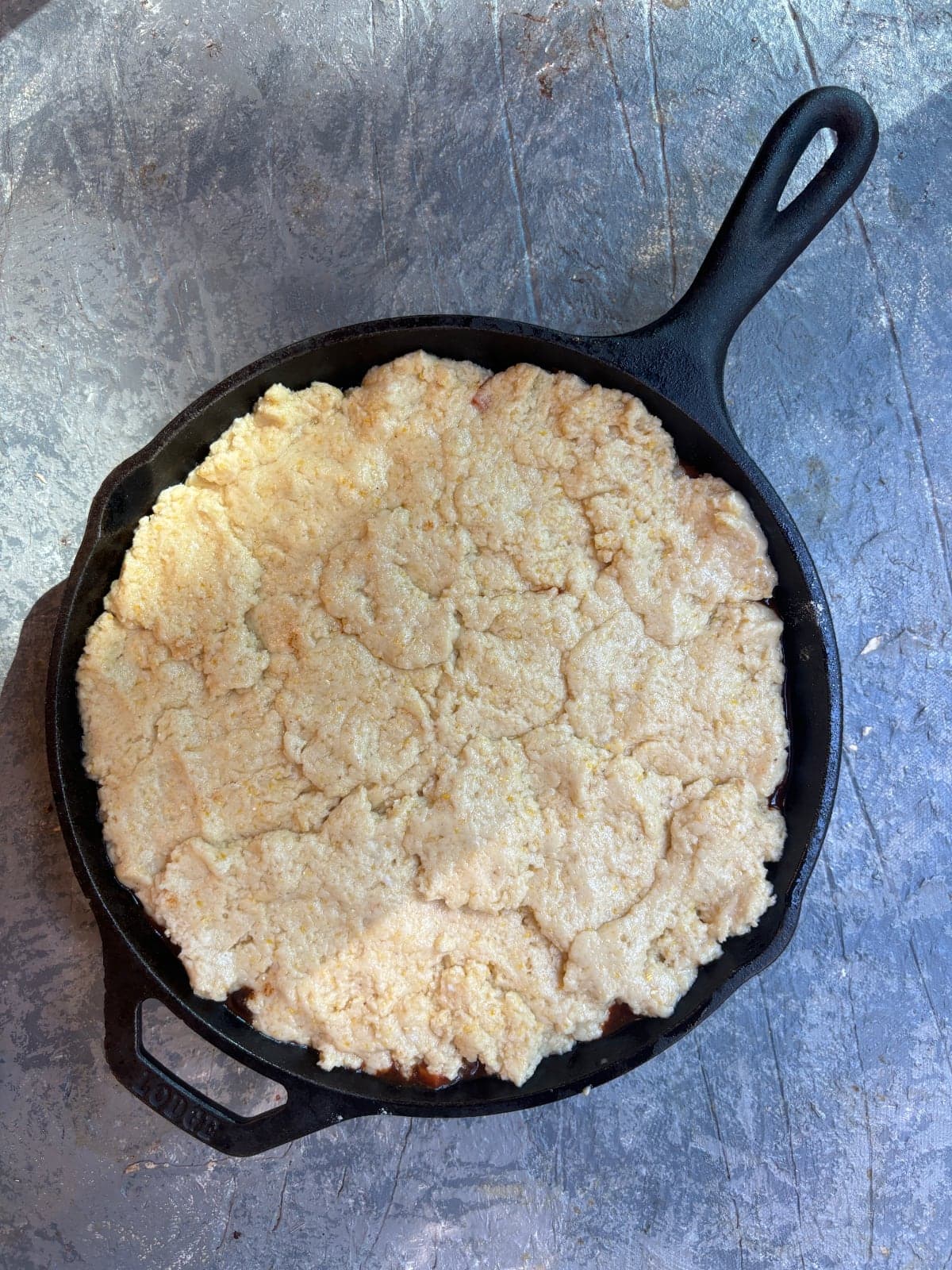 overhead image of a cast iron skillet filled with black bean chili and covered with cornbread batter