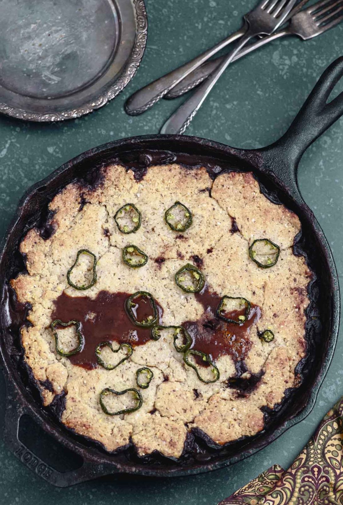 A chili cornbread casserole next to a silver plate and silverware.