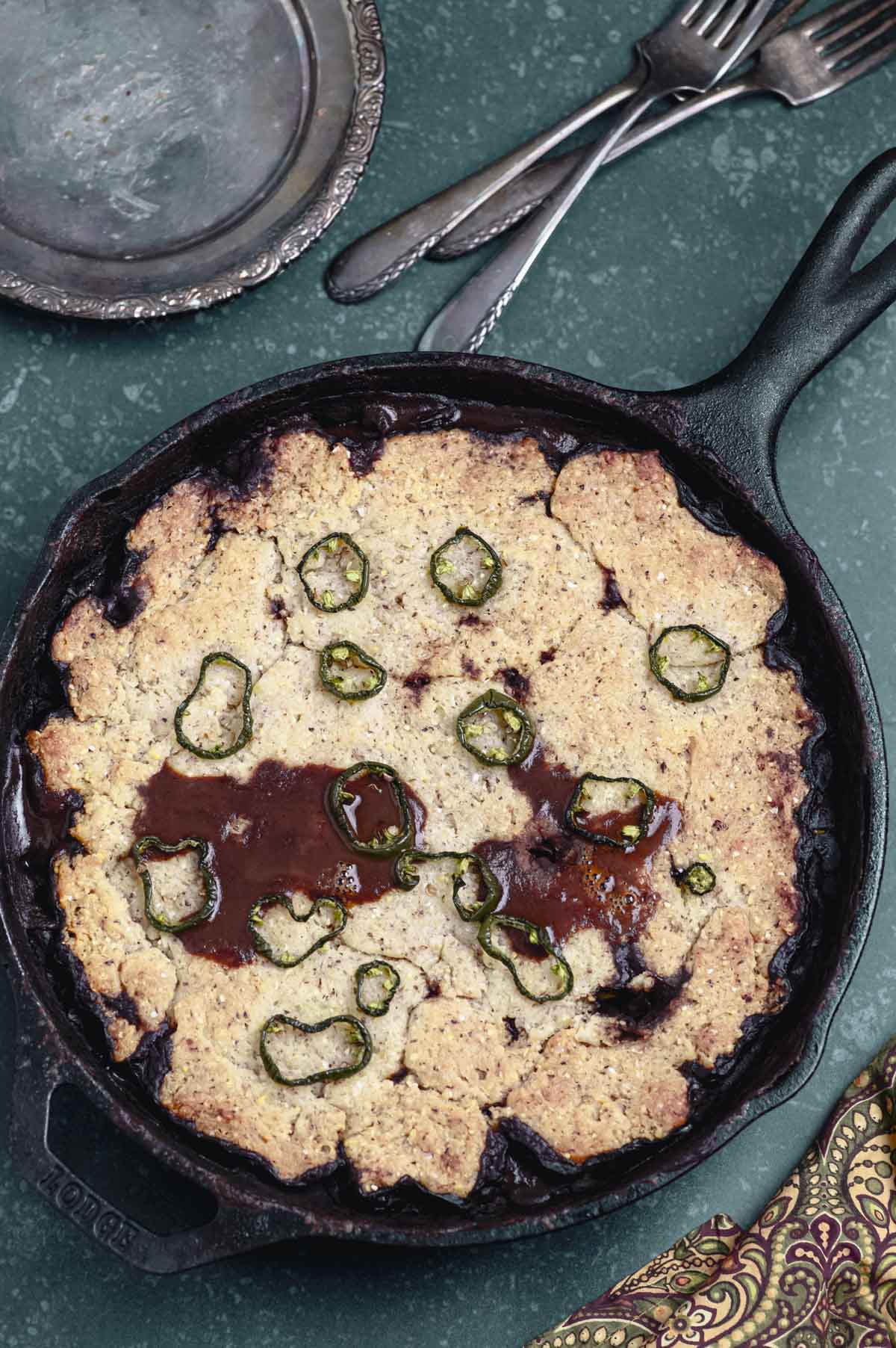 A chili cornbread casserole next to a silver plate and silverware.