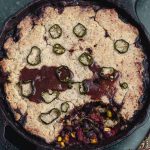 Close up view of a chili cornbread casserole in a cast iron pan
