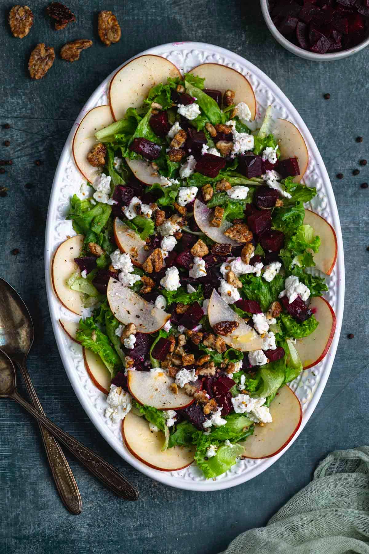 overhead image of a beet salad with goat cheese and pears on a white oval platter