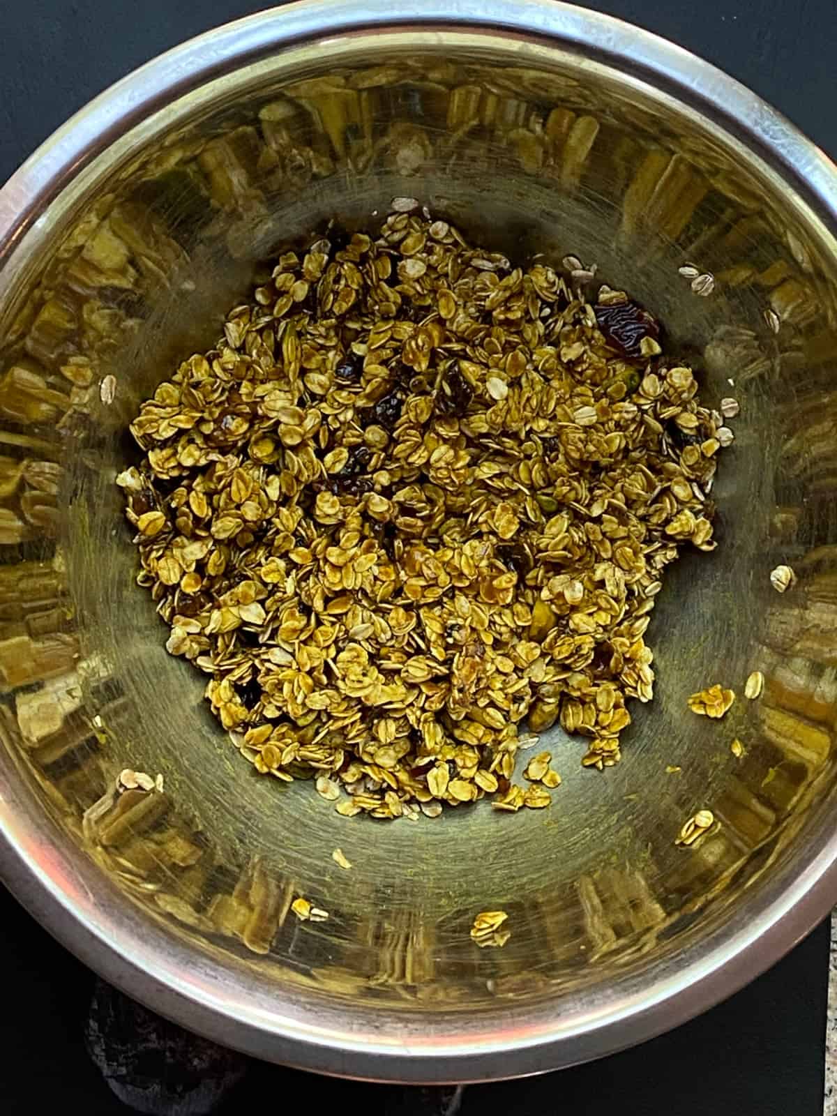 overhead image of a large mixing bowl with oats, pistachios and sesame seeds