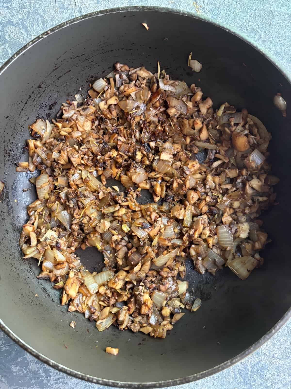overhead image of mushrooms and onions cooking in a nonstick skillet.