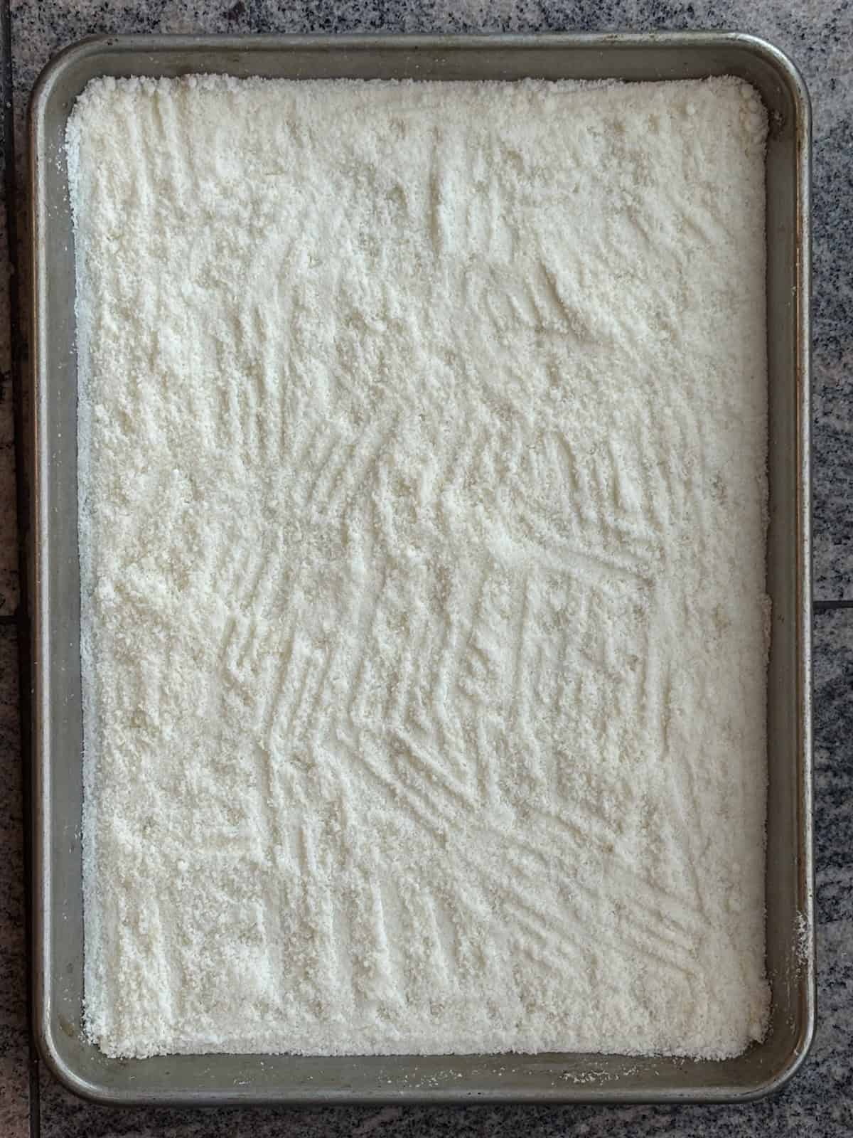 A baking sheet covered with grated parmesan cheese