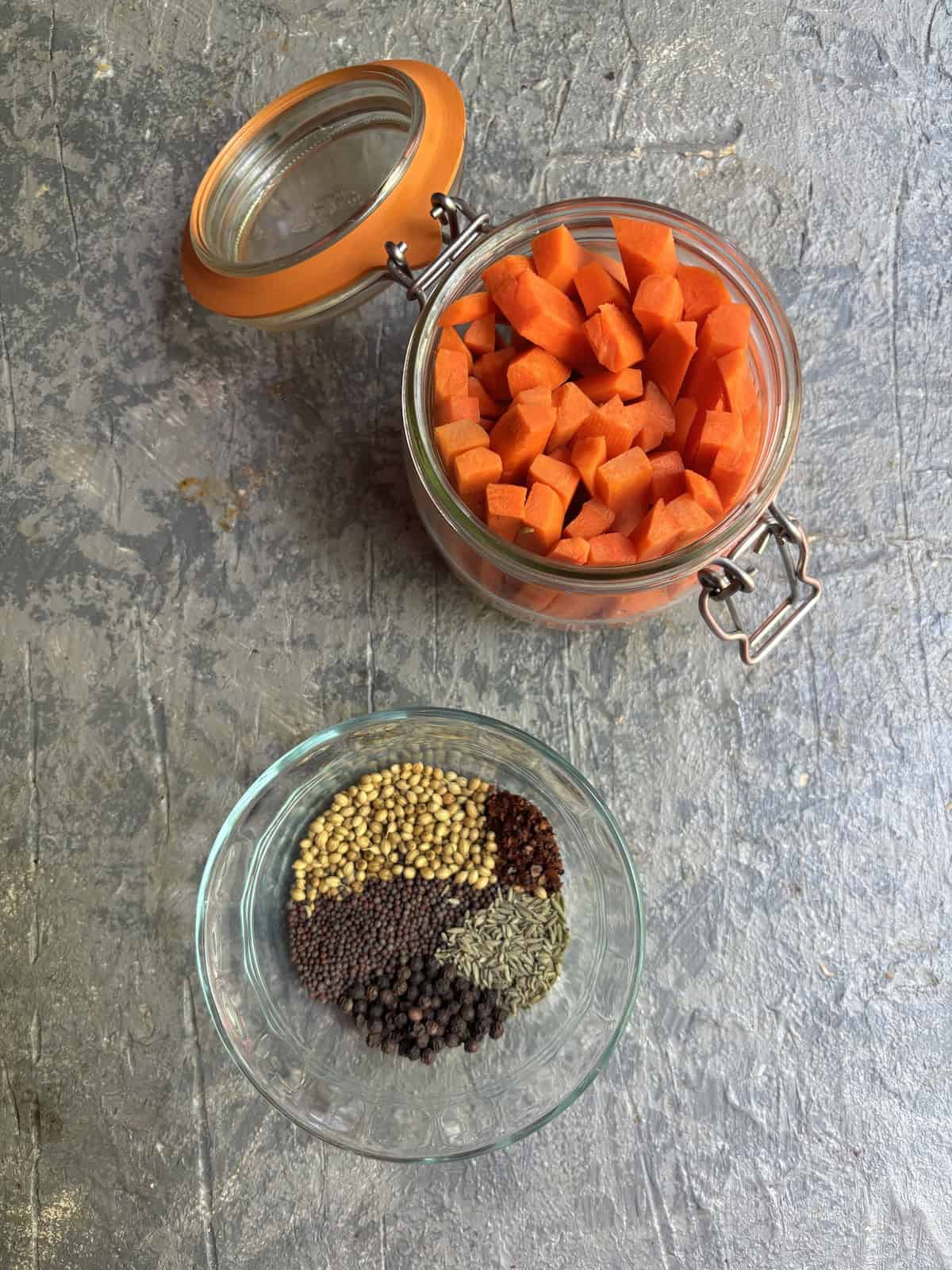 a jar filled with carrots and a small bowl with spices
