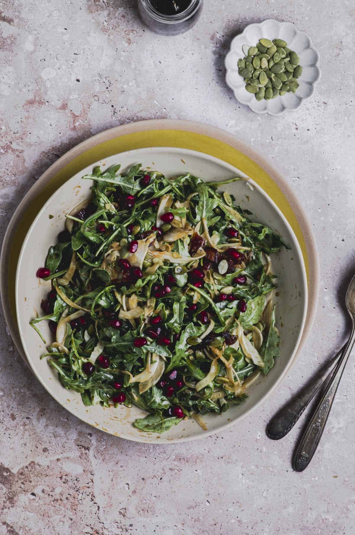 A bowl of fennel and arugula salad on top of a yellow plate.